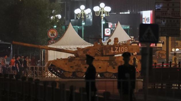 People watch a military tank passes along the Jianguomenwai Avenue in Beijing on Saturday. Many of the streets in the central part of China's capital were being shut down this weekend for a rehearsal for what is expected to be a large military parade on Oct. 1 to commemorate the 70th anniversary of Communist China.(Photo: AP)