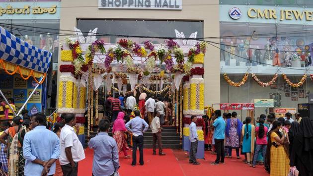 Customers stand out of a shopping mall which is decorated for the upcoming festive season, in Hyderabad. Amazon and Flipkart’s six-day festive sales are estimated to reach $3.8 billion, up from $2.9 billion last year, despite the wider economic slowdown, Forrester Research senior forecast analyst Satish Meena said. (Noah Seelam / AFP)