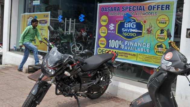 A customer walks inside a two-wheeler sales shop as special sales offer posters are displayed for the upcoming festive season, in Hyderabad. “It’s a good beginning... The likelihood is that we’ve almost reached the bottom and if the government continues to do its bit and corporates remain upbeat because of these announcements, things will start looking up,” India Ratings principal economist Sunil Sinha said. (Noah Seelam / AFP)