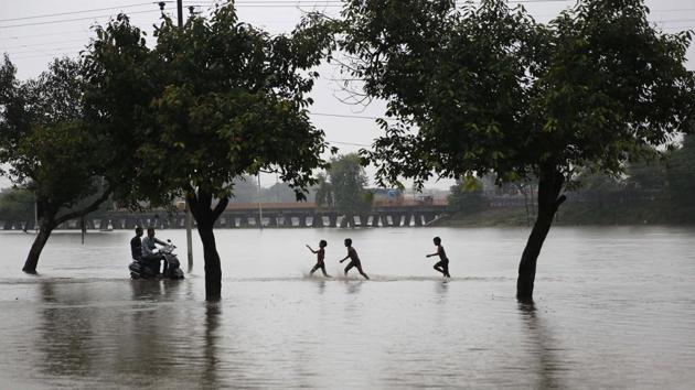 Boys play in the rain on a flooded street in Prayagraj. This year, rainfall is 8% more than the long period average (LPA), indicating that this monsoon will end with “above normal” rains. IMD had forecast in April that monsoon rainfall will be “near normal” at 96% of the LPA. (Rajesh Kumar Singh / AP)