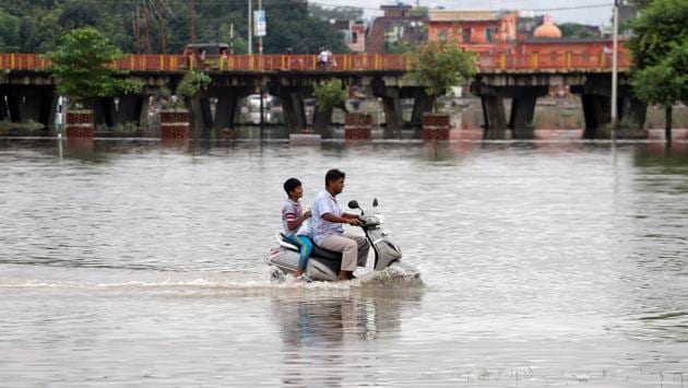 A man and a boy ride a scooter through a flooded road after heavy rains in Prayagraj. Relief Commissioner of Uttar Pradesh, GS Priyadarshi, also said that 294 houses have been damaged due to excessive rain in the area. He said that the government is constantly in touch with the weather department and district administrations to control water-logging problems. (Jitendra Prakash / REUTERS)
