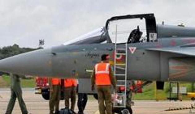Airport ground staff stand besides Tejas, India's first locally-built Light Combat Aircraft (LCA), before its induction into the Indian Air Force at the Hindustan Aeronautics Limited (HAL) Airport in Bengaluru. (Reuters photo)
