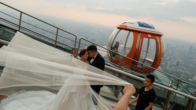 Newlywed couples pose for wedding pictures on top of the Canton Tower in the Haizhu district in Guangzhou. Wealth has transformed the city’s downtown, where skyscrapers dominate the skyline. The most prominent is the 604-metre tall Canton Tower, where newlyweds flock to shoot wedding photographs, as tourists look on. (Jorge Silva / REUTERS)
