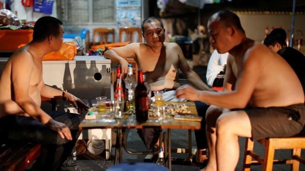 Men drink and chat outside of a shop in the traditional neighbourhood of Yuexiu in Guanghzou. By the evening, hawker stalls and small massage parlours light up dim alleys that come alive with chatter and beer drinking as friends try to beat the sultry summer heat. (Jorge Silva / REUTERS)