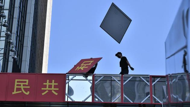 A protester removes the signage celebrating the 70th anniversary of communist China’s founding from a footbridge during a rally in the Admiralty district of Hong Kong. Hong Kong police shot a pro-democracy protester yesterday as the city was lashed by its worst unrest of the year. This was the first such incident in nearly four months of increasingly violent protests and threatened to strip the spotlight from China’s carefully choreographed birthday party. (Anthony Wallace / AFP)