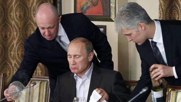 FILE - In this Friday, Nov. 11, 2011, file photo, businessman Yevgeny Prigozhin, left, serves food to Russian Prime Minister Vladimir Putin, center, during dinner at Prigozhin's restaurant outside Moscow, Russia. The U.S. sought to punish Russia on Monday, Sept. 30, 2019, for interfering with the November 2018 election by placing the yacht and private planes of a Russian financier, Yevgeny Prigozhin, on an international sanctions list along with employees of the Internet Research Agency that he has funded to spread false information on social media.(AP)