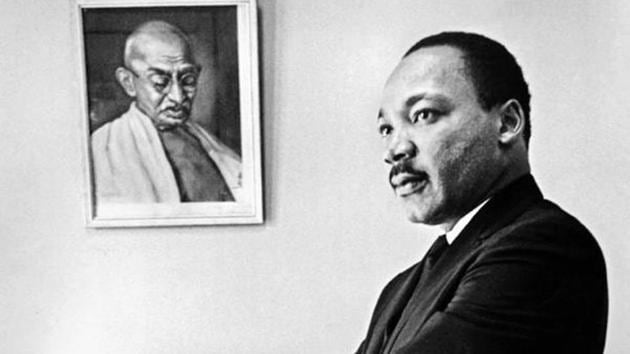Dr Martin Luther King, Jr stands next to a portrait of Mahatma Gandhi in his office in 1966.(Bob Fitch Photography Archive, Department of Special Collections, Stanford University Libraries)