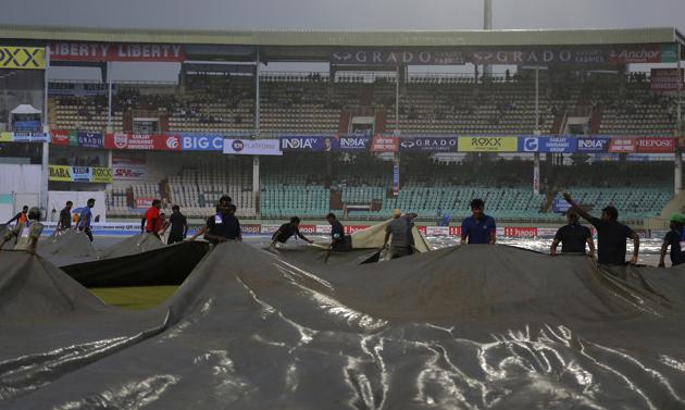 Ground staff pull rain covers as it rains during the first day of the first cricket Test match between India and South Africa in Visakhapatnam. (AP)
