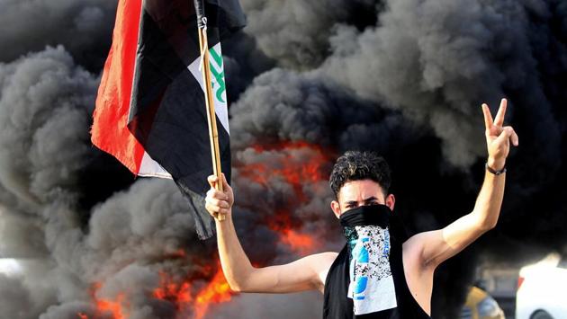 A demonstrator gestures as he stands close to burning tires blocking a road, during a protest over unemployment, corruption and poor public services, in Baghdad, Iraq. (Thaier al-Sudani / REUTERS)