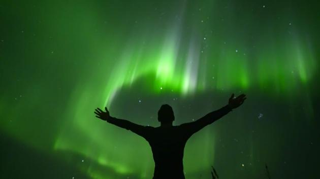 Indonesian surfer Edi Siswanto ,waves at northern lights in Unstad, Lofoten Islands, beyond Arctic Circle. (Olivier Morin / AFP)