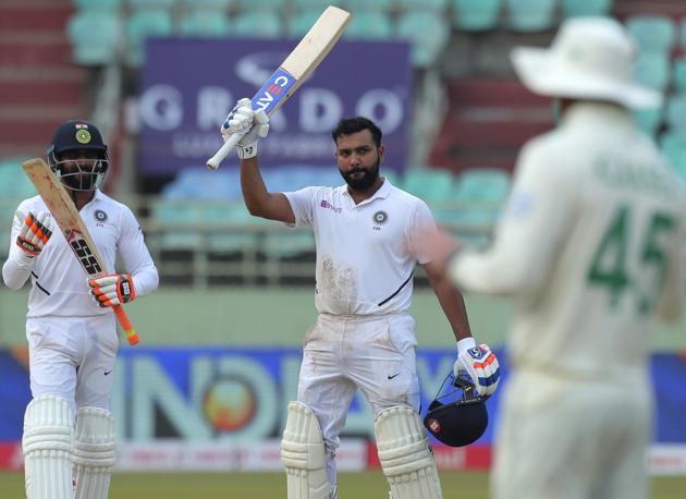 India's Rohit Sharma, center, raises his bat after scoring a century during the fourth day of the first cricket test match against South Africa in Visakhapatnam. (AP)