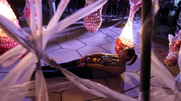 A woman lies underneath the work of Taiwanese artists Peng yu-hong and Yang Fang-Yi titled 'Weaving the Plastic Souls, at the Nuit Blanche Taipei 2019 in Taipei. (AP)