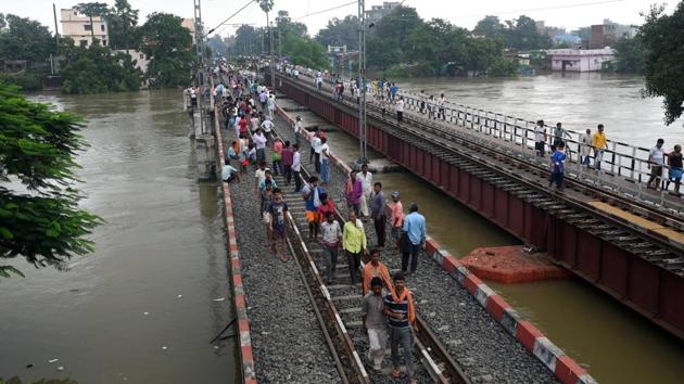 People walk on railway tracks after their train was stopped at Punpun station due to the Punpun river crossing the danger mark, in Patna, Bihar. (Parwaz Khan / HT Photo)