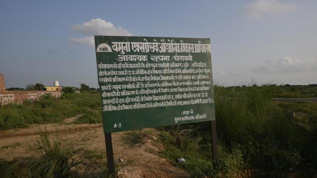 The agricultural fields in the village have the last standing crop, and boards put by Yamuna Expressway Industrial Development Authority (YEIDA) with a ‘statutory warning’ that the land has been acquired by the UP government for the Noida International Airport, Jewar. (Biplov Bhuyan/HT Photo)