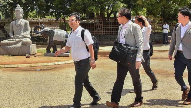 Officials walk past a Buddha statue installed at the entrance of the shore temple in Mamallapuram as part of the preparations for the informal summit between Prime Minister Narendra Modi and Chinese President Xi Jinping, to be held from October 11 to 13.(PTI PHOTO.)