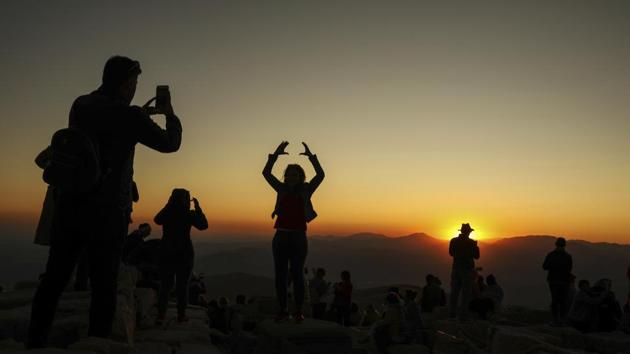 Visitors snap photos of the sunset and massive stone heads that stare down on them from the summit of Mount Nemrut, in Turkey’s southeastern Adiyaman province. (Emrah Gurel / AP)