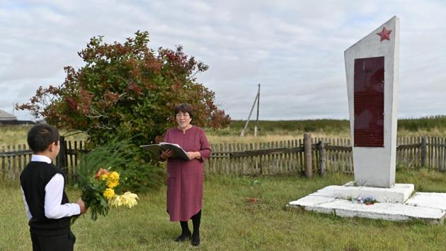 Ravil Izhmukhametov, 9, and teacher Uminur Kuchukova, 61, attend the ceremony on the first day of the new school year next to a WWII monument in the village of Sibilyakovo, Omsk region, Russia. Kuchukova has taught at the school for 42 years. She could have retired years ago, but continues to teach at once bustling school for the sake of its last pupil. When she leaves next year, the school will close. (Alexey Malgavko / REUTERS)