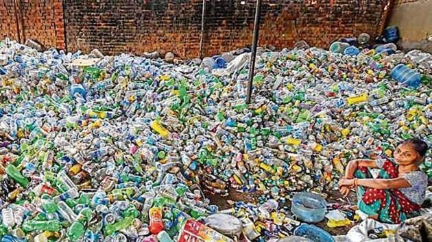 A woman sits among plastic bottles segregated for recycling.(PTI image)