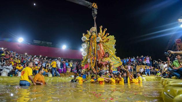 Devotees immerse an idol of goddess Durga into an artificial pond at CR Park. The idols of goddess Durga were for the first time immersed in an artificial pond instead of the Yamuna. The idol immersion protocol was followed by more than 500 Durga Puja committees in the city on Tuesday. Together, they gave up a ritual where idols were taken to the Yamuna as part of a procession and immersed there. (Amal KS / HT Photo)