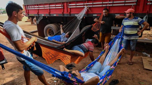 Trucker Erik Fransuer (L) rests on hammocks with others at a gas station. Fransuer spends months driving back and forth on highways that cut through the Amazon delivering soy or corn to river ports. “I like the freedom of being on the road,” Fransuer said. He spends at least 12 hours a day sitting in his big rig listening to fast-paced music as he bounces along the highways constructed nearly 50 years ago and somehow still not finished. (Nelson Almeida / AFP)