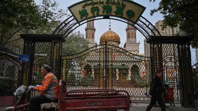 People walk past a mosque in Urumqi. While the official explanation ranges from urban development to the “standardisation” of old graves, overseas Uighurs say the destruction is part of a state crackdown to control every element of their lives.”This is all part of China’s campaign to effectively eradicate any evidence of who we are, to effectively make us like the Han Chinese,” said Salih Hudayar, who said the graveyard where his great-grandparents were buried was demolished. (Hector Retamal / AFP)