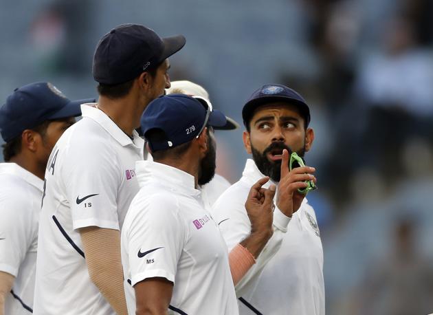 Indian cricketer Virat Kohli talks with teammates at the end of the second day of the second cricket test match between India and South Africa in Pune. (AP)