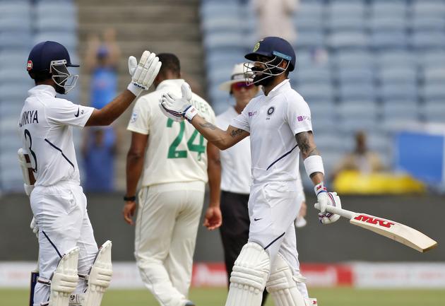 India's cricketer Virat Kohli, right, celebrates his hundred with Ajinkya Rahane during the second day of the second cricket test match between India and South Africa in Pune. (AP)