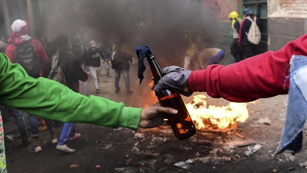 Demonstrators pass on a Molotov cocktail during clashes with riot police in Quito. Protests against fuel price hikes in Ecuador a week ago have escalated into violent clashes, leaving five protesters dead and leading the government to suspend two-thirds of its crude oil distribution. (Martin Bernetti / AFP)