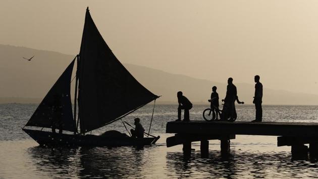 A fisherman sails past a dock where boys were fishing in the Cite Soleil district of Port-au-Prince, Haiti. Residents of Cite Soleil say access to basic services, jobs, and security has been declining and many are participating in protests calling for the resignation of President Jovenel Moise. (Rebecca Blackwell / AP)
