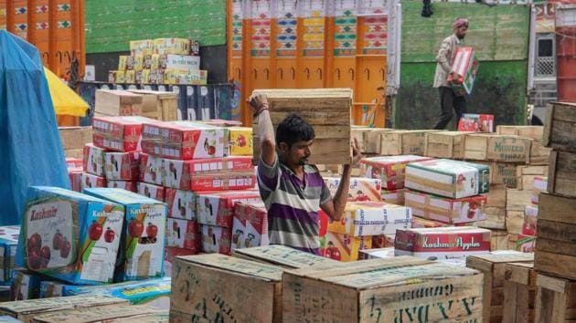 A worker carries a box of Kashmiri apples for sale at Narwal fruit market, on the outskirts of Jammu. (PTI)