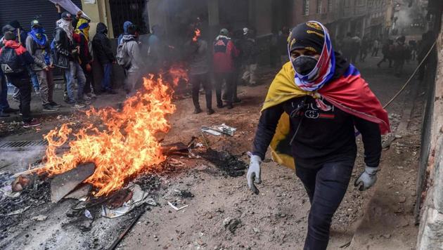A demonstrator wrapped in an Ecuadorean flag passes by a barricade set on fire during clashes with riot police in Quito, as thousands march against Ecuadorean President Lenin Moreno's decision to slash fuel subsidies. Unions and other groups alongside thousands of farmers and indigenous people are protested on the streets of the capital Quito. The government doubled fuel prices as part of an agreement with the International Monetary Fund to obtain loans despite the country’s high public debt. (Martin Bernetti / AFP)