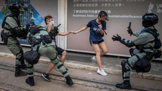 Police chase down a couple wearing face masks in the central district in Hong Kong, a day after the city's leader outlawed face coverings at protests invoking colonial-era emergency powers not used for half a century. (Nicolas Asfouri / AFP)