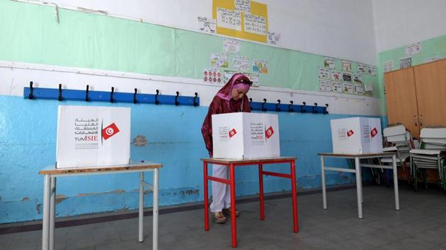 A woman stands behind a voting booth at a polling station in the capital Tunis during the third round of legislative elections since the North African country's 2011 revolution. Some seven million voters are expected to head to polling stations, just weeks after the first round of the presidential polls swept aside the post-Arab Spring political establishment. (Fethi Belaid / AFP)