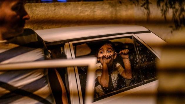 boy looks from a car as they prepare to leave after a mortar sent from Syrian side hit their house in Akcakale in Sanliurfa province. Turkey has launched a broad assault on Kurdish-controlled areas in northeastern Syria, with intensive bombardment followed by a ground offensive made possible by the withdrawal of US troops. (Bulent Kilic / AFP)