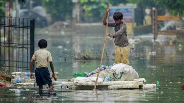 A rag picker rows a makeshift boat as he collects plastic bottles floating on floodwaters at Rajendra Nagar area, in Patna, Bihar. (PTI)