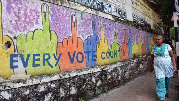 A woman passes by a wall mural that urges citizens to cast their vote ahead of the Maharashtra state assembly elections, near Masunda Lake, in Thane, Maharashtra. (Praful Gangurde / HT Photo)