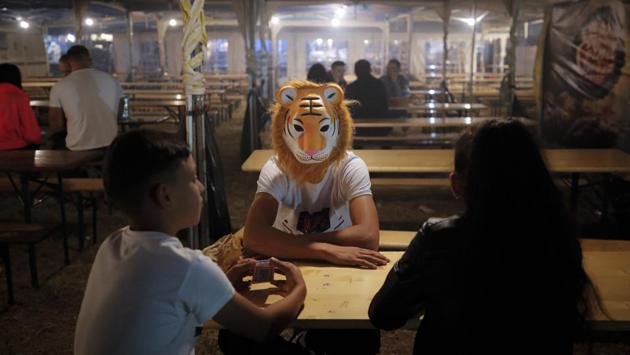 Children, one wearing a tiger mask, sit at a table in the food area of an autumn fair in Titu, southern Romania. Thousands flock to fields outside small cities, where entertainment areas are set up from mid-week until the weekend. (Vadim Ghirda / AP)