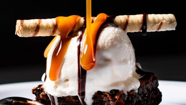 A scoop of Vanilla ice cream with brownie served with caramel sauce. (unsplash)