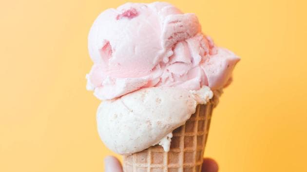 A large scoop of strawberry and vanilla ice cream in a waffle cone. (unsplash)