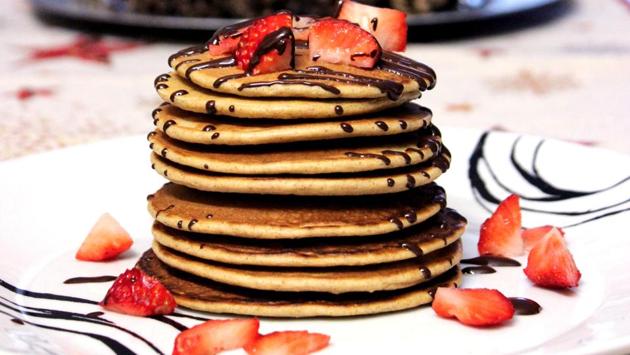 A layer of pancakes served with strawberries and chocolate syrup. (unsplash)