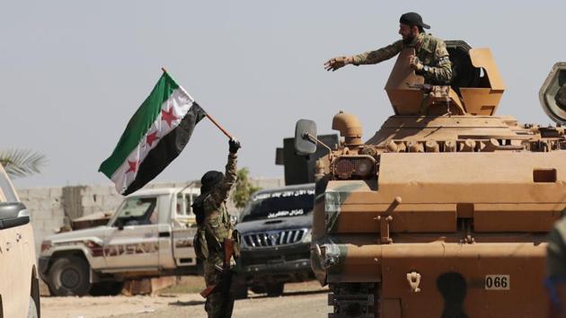 A Turkey-backed Syrian rebel fighter holds the Syrian opposition flag near the border town of Tel Abyad. Turkey-backed Syrian opposition forces took control of Tel Abyad’s city center and cleared it of Kurdish fighters. Tel Abyad is the two second border town at the focus of the ongoing Turkish offensive. (Khalil Ashawi / REUTERS)
