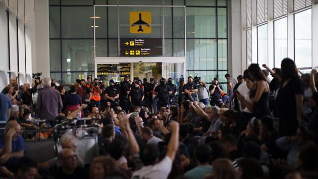 Police officers stand by a doorway as protestors sit down blocking access to El Prat airport. Barcelona’s international airport became the focal point of the protests. As thousands rallied at its entrance, riot police charged at the crowd on several occasions using batons and firing foam balls to prevent the risk of a forced mass entry, police said. At least three people were arrested in the region. (Emilio Morenatti / AP)