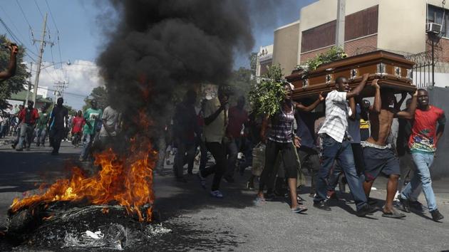 Mourners walk past burning tires carrying the coffin of a man killed during a demonstration, in Port-au-Prince, Haiti on October 16, 2019. Funerals for 11 of at least 20 people killed were held in six cities. At least two people were injured in a protest in the capital that broke out when presidential guards tried to block a road near where hundreds had gathered around the coffins of two victims. (Rebecca Blackwell / AP)
