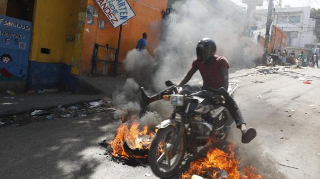 A man drives his motorcycle through a burning barricade during anti-government protests in Port-au-Prince, on October 11. Haitians have complained of a leadership vacuum given Moise’s rare appearances during this crisis. The last time Moise spoke publicly before Tuesday was nearly three weeks prior in a pre-recorded 2 a.m. televised address. (Rebecca Blackwell / AP)