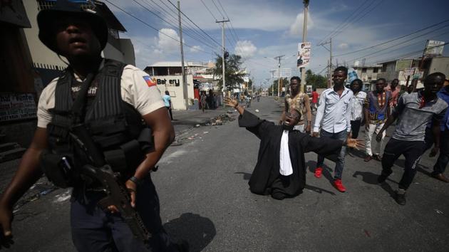 Paseus Juvensky St. Fleur, who trained as a lawyer and is now an activist working for social justice, drops to his knees as protestors trying to set up a barricade across a major road argue with police trying to stop them, in Port-au-Prince. Opposition leaders have rejected Moïse’s call for unity and dialogue and created a nine-person commission they say would be responsible for overseeing an orderly transition of power. (Rebecca Blackwell / AP)