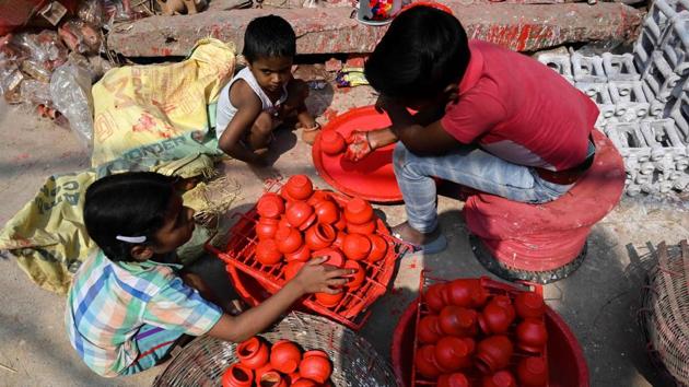Children colour earthen pots along a roadside, at Kumhar Gram. The finished products are loaded onto rickshaws dotted around the congested pathways to be taken to nearby markets and other buyers. (Money Sharma / AFP)