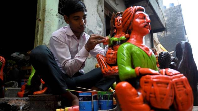 A boy colours a decorative item made of clay outside his residence at Kumhar Gram. The rickshaw drivers must carry their cargo while navigating the winding alleys filled with stacks of dry clay, finished or unfinished products, and people like this boy painting them. (Money Sharma / AFP)