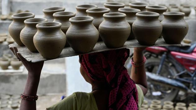 A woman carries clay pots for drying on an open space, at Kumhar Gram in New Delhi. Known as the “Potter’s Village”, the settlement is home to around 500 families from the traditional pottery community, who moved to the area half a century ago. (Money Sharma / AFP)