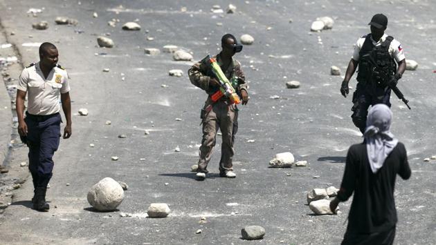 A protester in camouflage carries a toy weapon during a protest, as two police officers walk past him. The opposition rejected assurances and calls for dialogue. “Moise does not have the moral authority to attack the guardians of the system of exclusion that we are fighting today as his electoral campaign was financed by these people,” said opposition leader Andre Michel. (Dieu Nalio Chery / AP)
