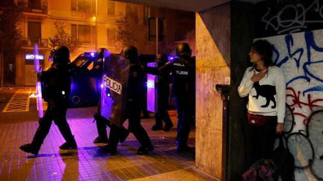 A woman takes cover as police officers walk past during a protest after a verdict in a trial over a banned Catalonia’s independence referendum, in Barcelona, Spain. (Rafael Marchante / REUTERS)